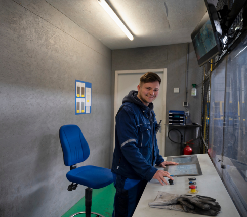 Danylo werkt als operator in een technische ruimte met bureau en schermen, zichtbaar trots op zijn werkplek