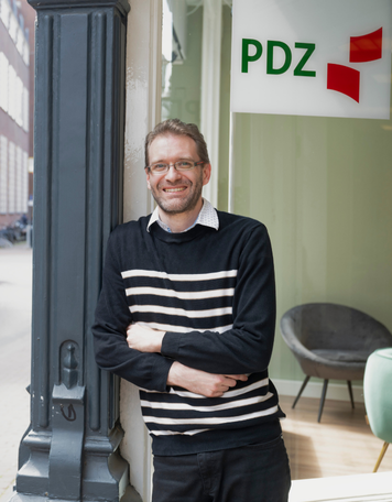 Kandidaat staat glimlachend voor vestiging van PDZ Uitzendbureau.