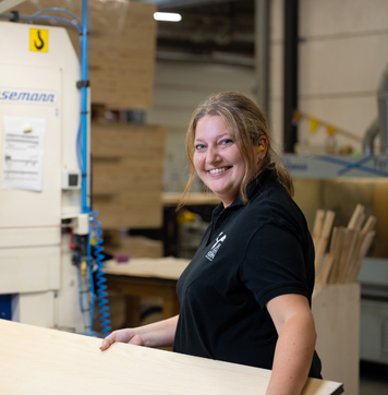 Operator werkt lachend met houten platen in een houtbewerkingsbedrijf