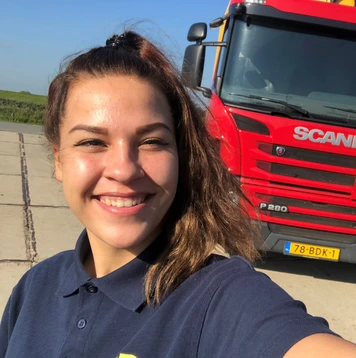 Chauffeur maakt glimlachende selfie voor rode Scania-vrachtwagen.