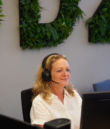 Receptionist met headset aan het werk achter de balie.