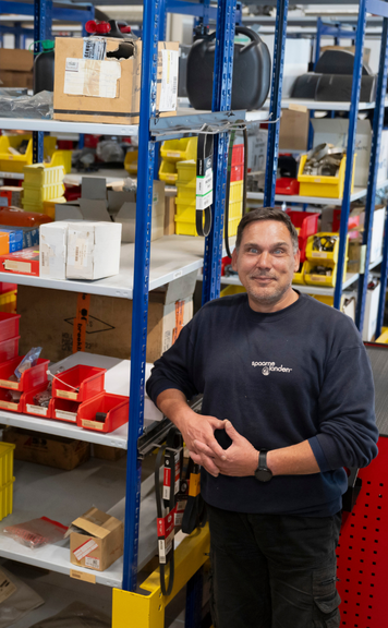 Logistiek medewerker in magazijn tussen stellingen met onderdelen.