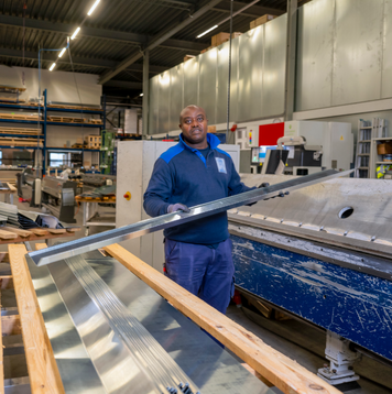 Productiemedewerker werkt met metalen platen in een industriële werkplaats.