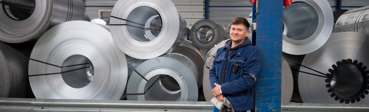 Operator in werkjas bij rollen metaal in industriële omgeving