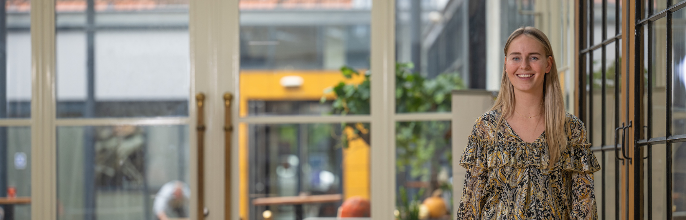 Accountmanager staat glimlachend in een moderne kantooromgeving.