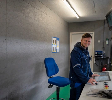 Technisch medewerker bedient een machine via een bedieningspaneel in een industriële werkomgeving.