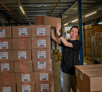Orderpicker stapelt dozen in een magazijn.