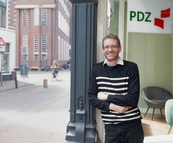 Kandidaat staat glimlachend voor vestiging van PDZ Uitzendbureau.