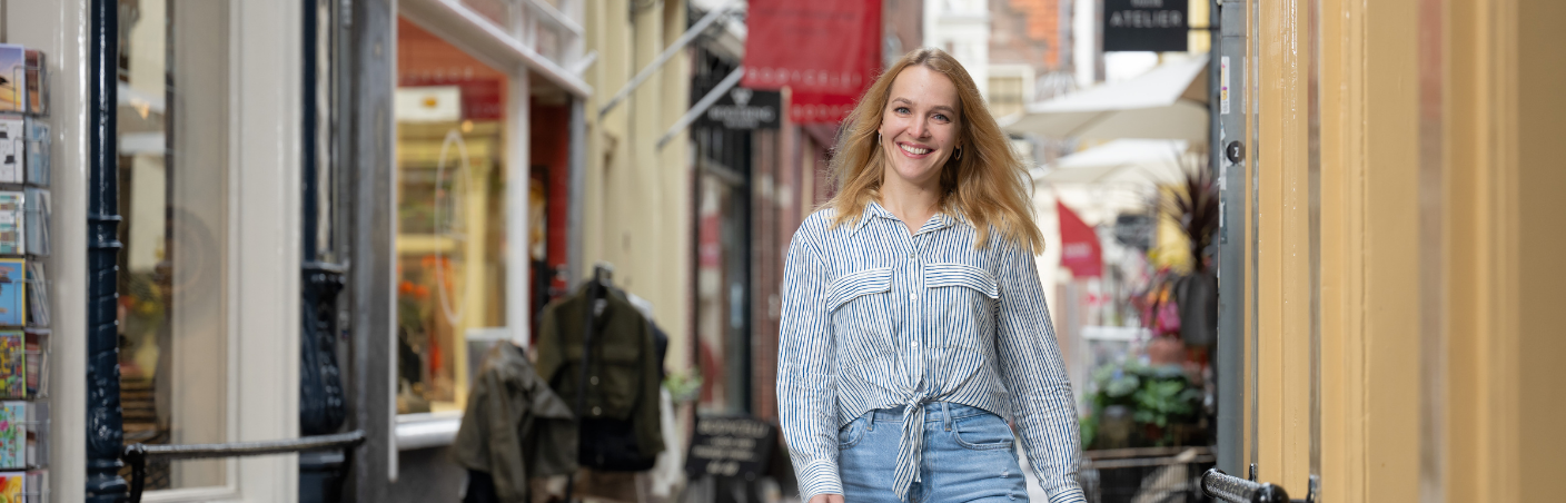 Kandidaat loopt lachend door een winkelstraat.
