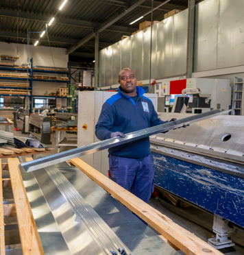 Assemblagemedewerker werkt met metalen profielen in de productiehal.