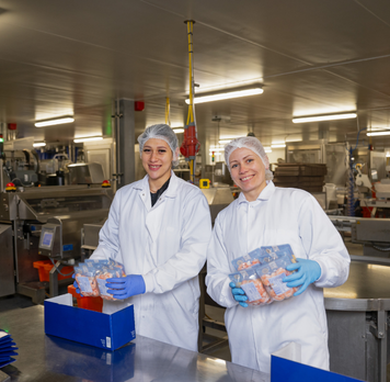 Twee productiemedewerkers verpakken producten in een fabriek.