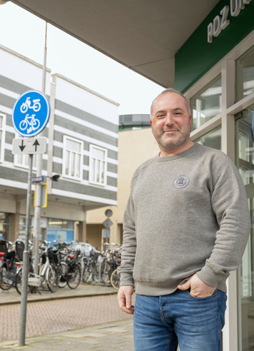 Logistiek administratief medewerker staat buiten bij een kantoor.