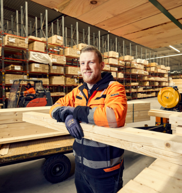 Magazijnmedewerker van Stiho leunt tegen stapel hout in grote opslaghal.