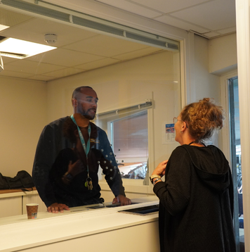 Woonbegeleider in gesprek met een collega bij de receptiebalie