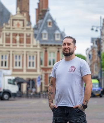 Kandidaat buiten in de stad met historische gebouwen op de achtergrond.