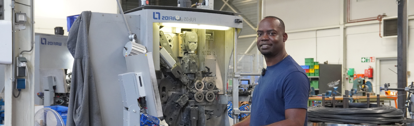 Verkoopmedewerker staat bij een machine in een industriële werkomgeving.
