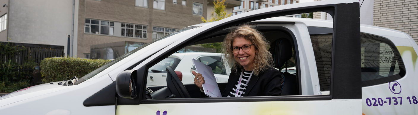 Verpleegkundige van Madeliefje Thuiszorg zit met documenten in een dienstauto.