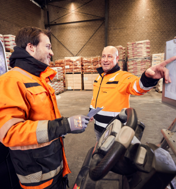 Magazijnmedewerker geeft uitleg aan collega in het magazijn.