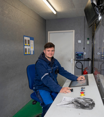 Operator bedient een machine vanuit een controlekamer.