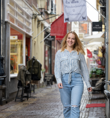 Kandidaat loopt lachend door een gezellige winkelstraat.