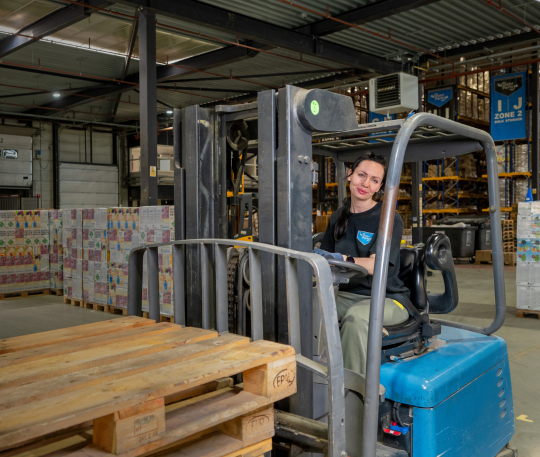 Heftruckchauffeur aan het werk in een magazijn met pallets.