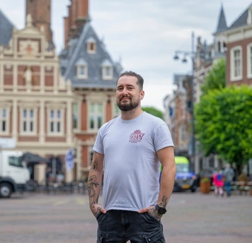 Teamleider logistiek buiten in de stad met historische gebouwen op de achtergrond.