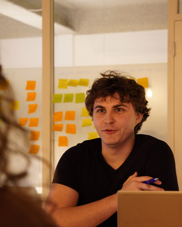 Accountmanager in gesprek tijdens overleg met laptop en notities op de achtergrond.