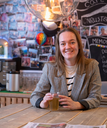 Intercedent met drankje aan tafel in creatieve kantoorruimte met fotowand.
