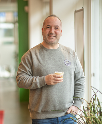 Man glimlacht met een kopje koffie op kantoor