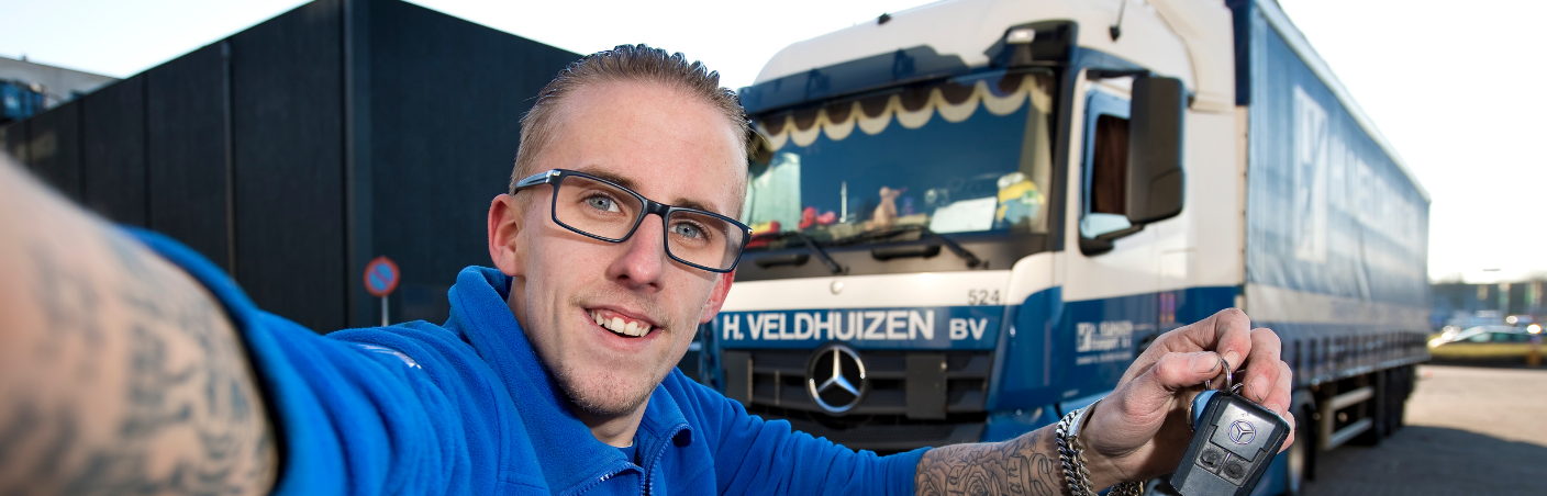 Chauffeur maakt selfie met sleutels voor zijn vrachtwagen.
