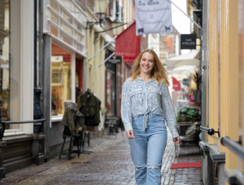 Kandidaat loopt lachend door een gezellige winkelstraat.