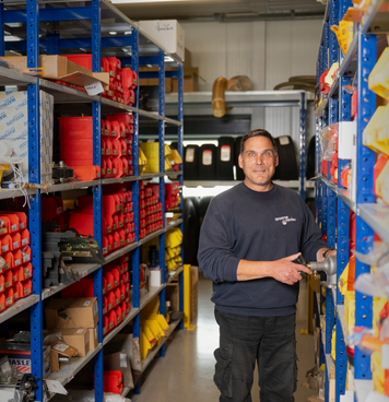 Magazijnmedewerker werkt tussen volle schappen met onderdelen in het magazijn.