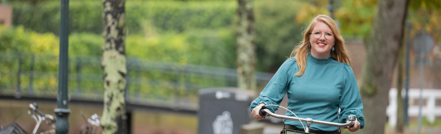Kandidaat fietst lachend door een groene omgeving.