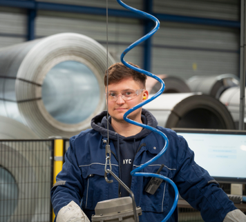 Operator met veiligheidsbril werkt aan een machine in een industriële hal