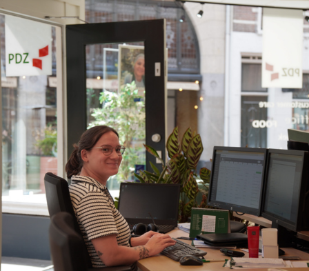 Intercedent zit achter haar bureau en werkt aan de computer op kantoor.