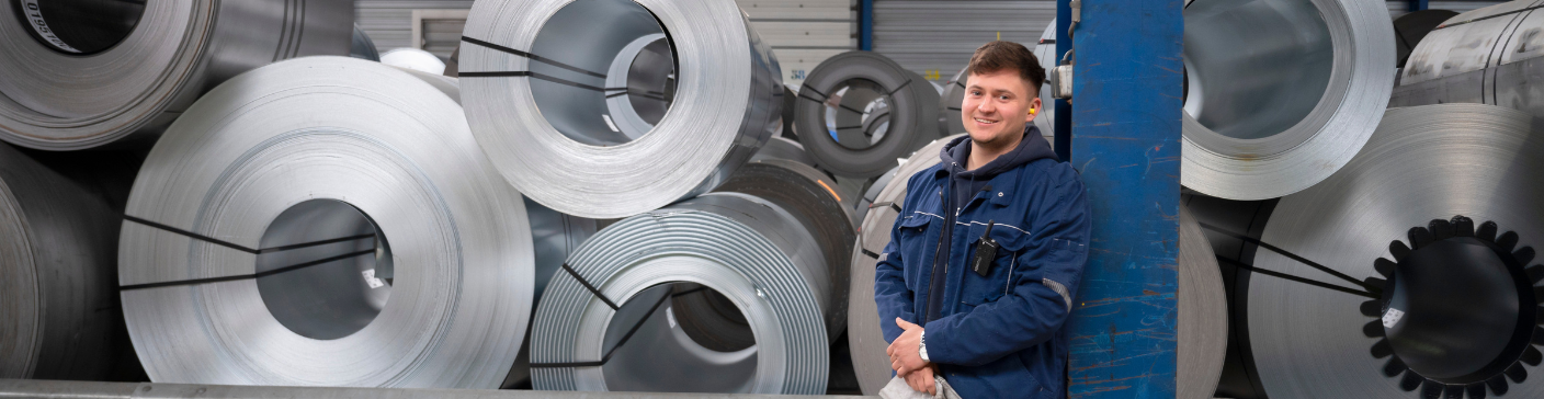 Operator in work coat near rolling metal in an industrial environment