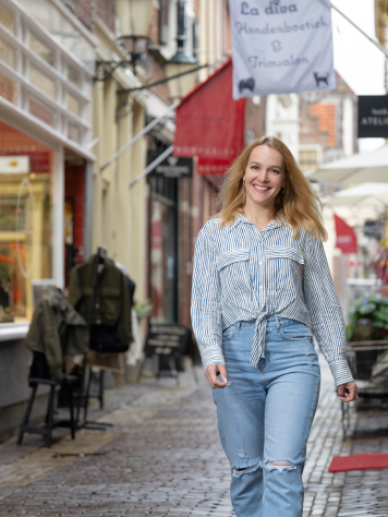 Kandidaat loopt lachend door een gezellige winkelstraat.
